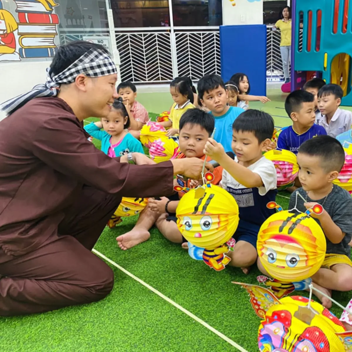 Đèn lồng Trung Thu — Cô phát từng chiếc đèn lồng con ong cho các bé mầm non trước giờ rước đèn.