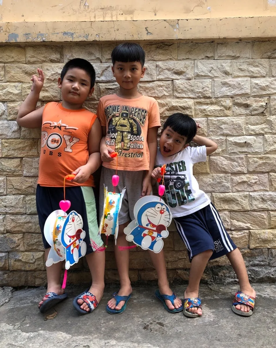 Đèn lồng Trung Thu — Ba bé trai khoe đèn lồng Doraemon trước khi đi rước đèn buổi tối.