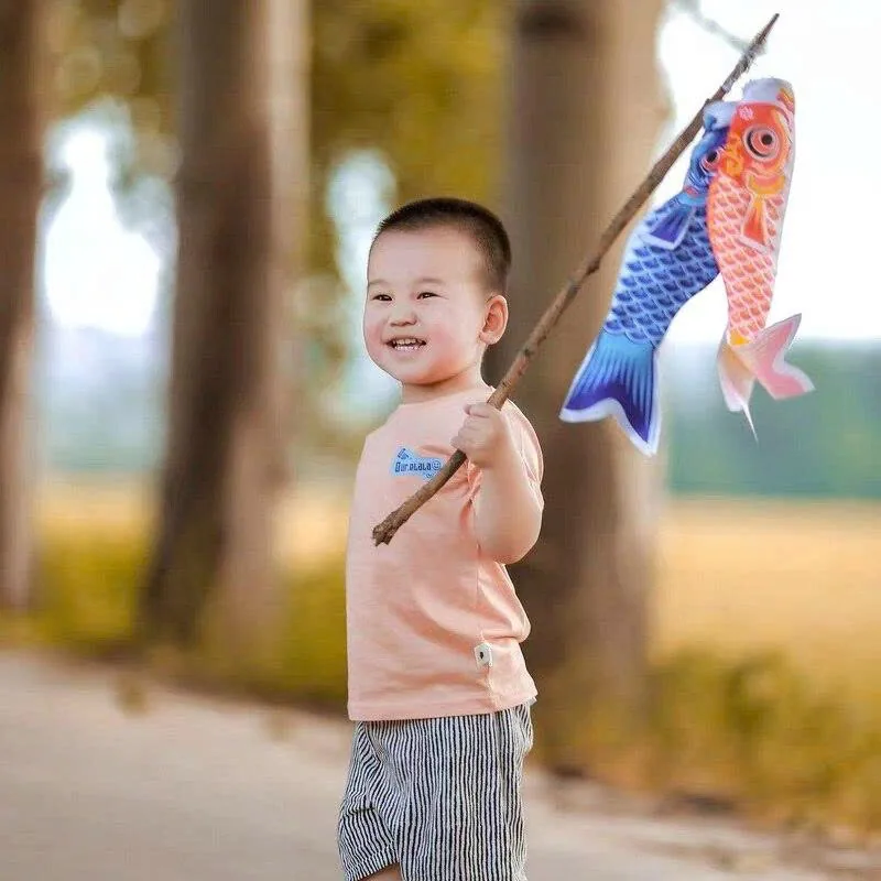 Bé rước cờ cá chép Nhật Bản koinobori ngoài trời dịp Tết Thiếu nhi